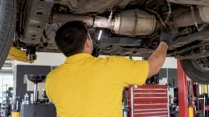 Technician inspecting catalytic converter and sensors