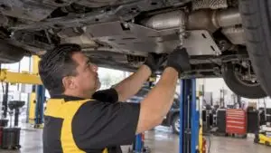 Technician installing catalytic converter shield