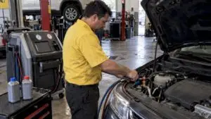 Technician checking a car’s A/C service connections