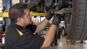 Technician inspecting a car’s front suspension