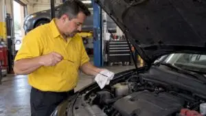 Technician checking engine oil with dipstick